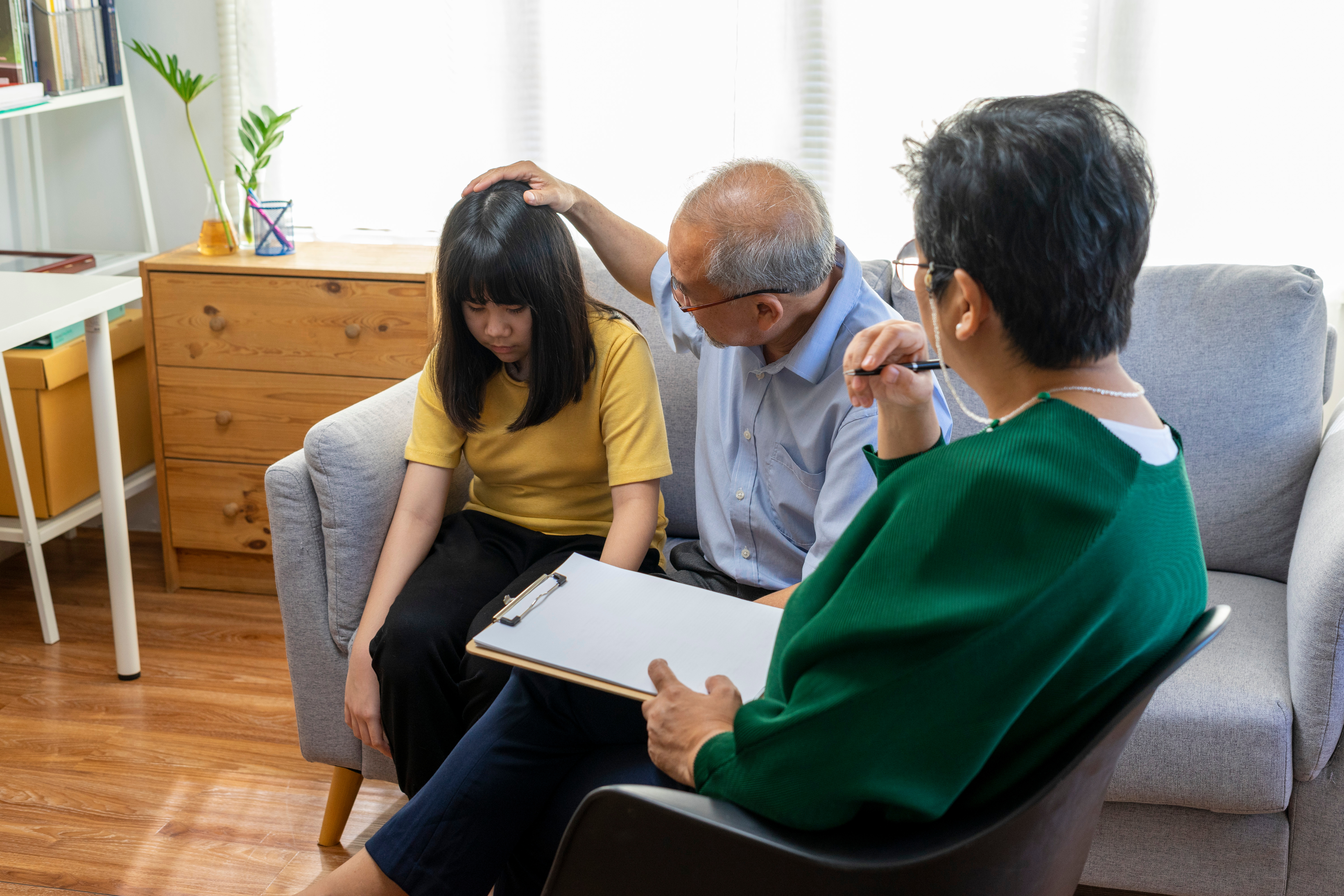 Parents telling the psychologist about family or child problems. Depressed girl and her parent or grandpa having session with psychiatrist in clinic.